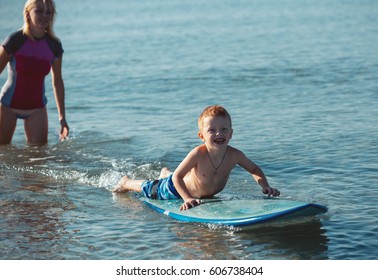 Athletic Girl With Little Boy Teaching Him Surfing