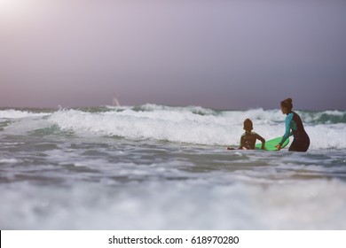 Athletic Girl With Little Boy Teaching Him Surfing