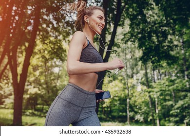 athletic girl running in the Park and doing exercises Jogging - Powered by Shutterstock