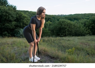 An Athletic Girl With A Slender Figure Performs Exercises With An Elastic Band, Pulling It With Her Hands