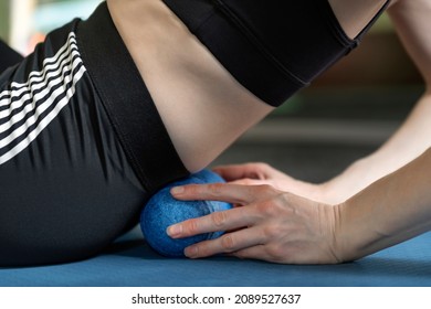 Athletic girl using roller to roll out small of the back muscles. Lumbar massage with ball for MFR. Side view.