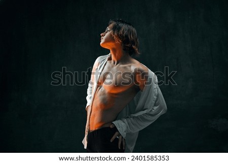 Athletic, handsome young man with muscular body against dark textured studio background. Young man in shirt and boxers. Concept of men's beauty, health, body art, aesthetics, care, sportive lifestyle