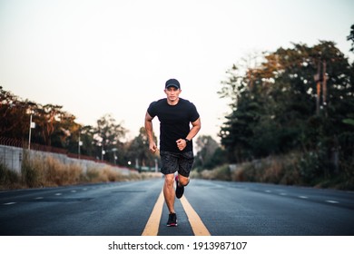 Athletic healthy young man running on the road. Sportive Asian Male runner sprinting outdoors. Full length shot. Healthy lifestyle - Powered by Shutterstock