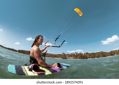 Athletic kite surfer stands in water with wakeboard