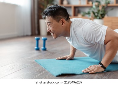 Athletic korean mature man doing push-ups on sports mat at home, working out core and hands muscles, copy space. Muscular and strong middle aged man exercising indoors - Powered by Shutterstock