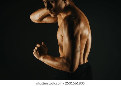 Athletic male model displaying a fit, muscular torso with defined abs and arm muscles, captured in a powerful pose against a dark background. - Powered by Shutterstock