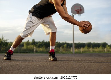 Athletic Male Playing Basketball Outdoors. Man Dribbling Ball At Court