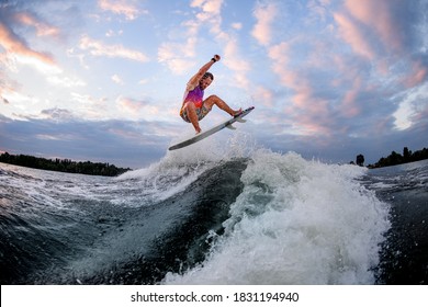 athletic man in bright clothes actively riding large wave doing jumps and tricks on the surf style wakeboard - Shutterstock ID 1831194940