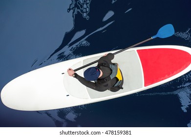 Athletic Man In A Diving Suit Stand Up Paddle Board On The River In The City SUP, View From Above