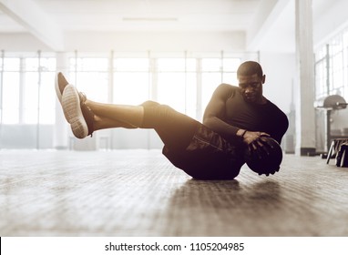 Athletic Man Doing Abdomen Exercise On The Floor. Man Doing Workout Using A Medicine Ball At The Gym.