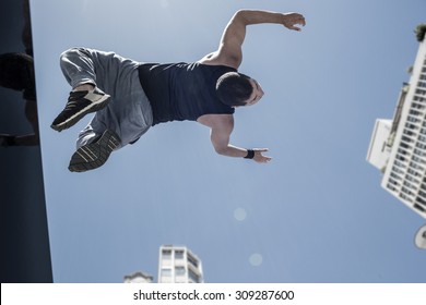 Athletic Man Doing Back Flip In The City On A Sunny Day