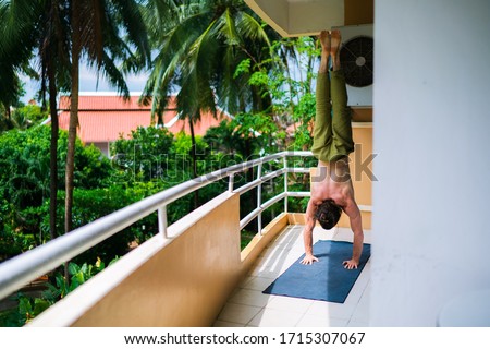 Athletic man doing a core workout on a balcony with a view on a green garden
