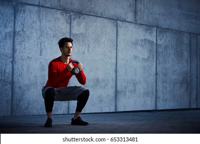 Athletic man doing kettlebell squats 