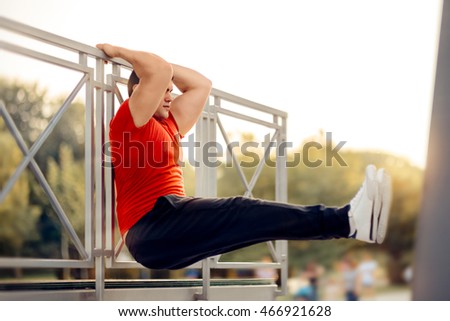 Athletic Man Doing Pull Up Bar Leg Raises - Fitness male model exercising outside