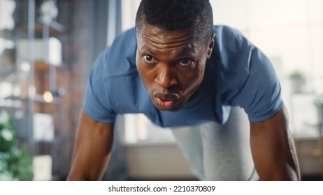 Athletic Man Doing Push Up Exercises and Using Mobile Smartphone as Timer. Authentic Male Doing Workout, He is Training at Home with Minimalistic Interior. Health and Fitness Concept.
