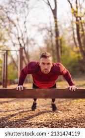 Athletic Man Doing Push Ups While Exercising In Street Workout Park On A Sunny Spring Day