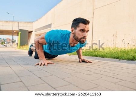 Athletic man doing pushup exercise in a city during street workout