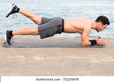 Athletic Man During Forearm Plank Exercise Outside On The Waterfront 