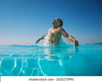 Athletic Man Emerging With A Splash From Rippling Blue Water