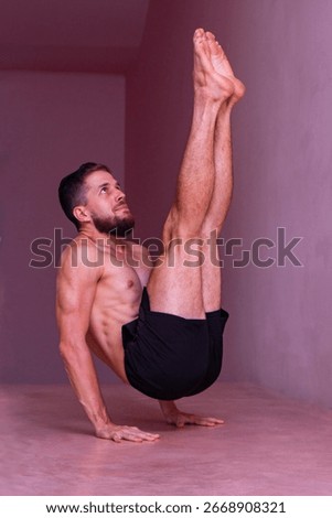Athletic man holds advanced core balance on hands with legs lifted. Concept of strength, focus, discipline, control, endurance and body mastery.