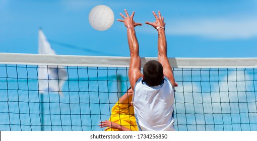 Athletic man jumping to make wall block at beach volleyball net.  - Powered by Shutterstock