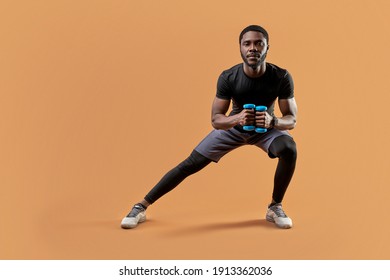 athletic man lunges with dumbbells in hands, do sportive exercises, lead healthy lifestyle, look at camera, isolated on brown background - Powered by Shutterstock