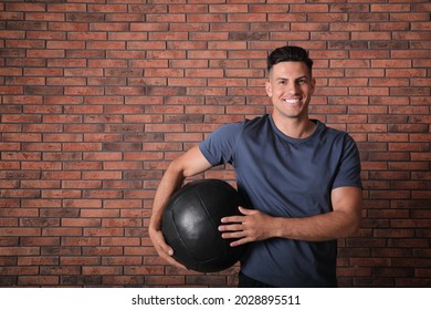 Athletic Man With Medicine Ball Near Red Brick Wall
