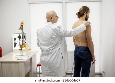 Athletic man on examination by physical therapist in medical office. Doctor examines patient's back and appoints physiotherapeutic treatment. Concept of back pain - Shutterstock ID 2146304639