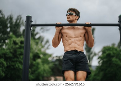 Athletic man performing pull ups on a bar outdoors, focusing on exercising biceps, lateral muscles, and shoulder strength.