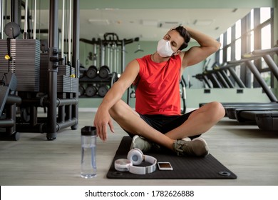 Athletic Man With Protective Face Mask Stretching His Neck While Warming Up For Sports Training In A Gym. 