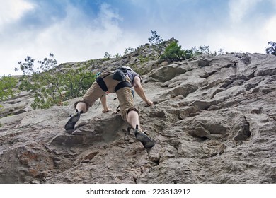 Athletic Man Rock Climbing On A High Rock Wall