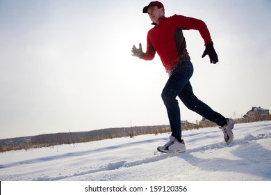 Athletic  Man Running In Winter Day On Snow Road