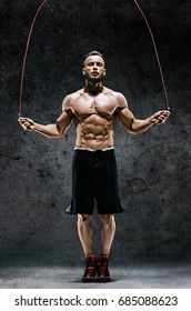 Athletic Man Skipping With A Jump Rope On Dark Background. Best Cardio Workout 