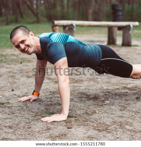 Athletic man smiling while doing pushups outdoor