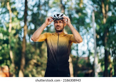 Athletic Man In Sport Clothes Wearing Helmet Holding His Glasses While Getting Ready To Ride A Bike Outdoors. Concept Of People, Hobby And Recreation. Portrait Of A Cyclist In An Active Wear.