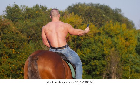 Athletic man with strong bare back riding a horse in nature