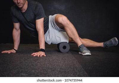 Athletic man using a foam roller to relieve sore muscles after a workout. 