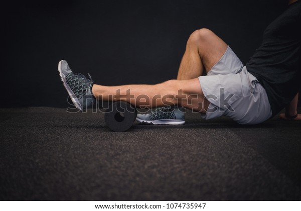 Athletic man using a foam roller to relieve sore muscles\
after a workout. 
