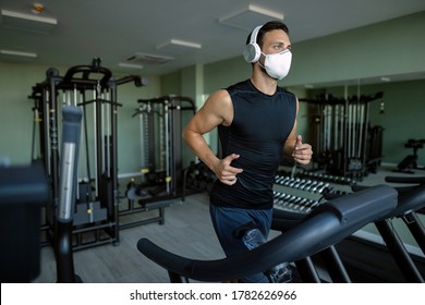 Athletic Man Wearing Face Mask While Running On Running Track In Health Club During Coronavirus Epidemic. 