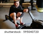 Athletic man which adjusts the rowing machine in gym