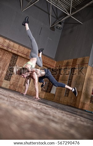 athletic man and woman doing gymnastic elements in the handstand in the gym