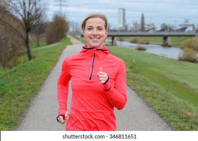 Athletic Middle Aged Blond Woman Jogging Along The Dike And Smiling At The Camera.