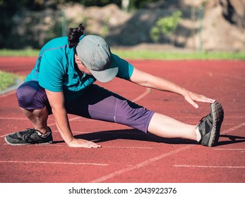 Athletic Middle Aged Woman Stretching On Red  Running Track Before Training, Healthy Fitness Lifestyle 