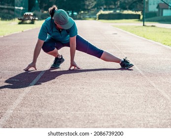 Athletic Middle Aged Woman Stretching On Red  Running Track Before Training, Healthy Fitness Lifestyle 