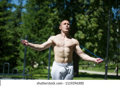 Athletic muscular man jumping with a rope, workout outdoors at sunny day - Powered by Shutterstock