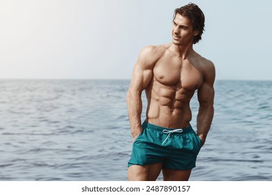 Athletic, muscular man in swim shorts posing at the beach.

 - Powered by Shutterstock