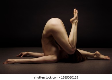 Athletic natural woman body on dark background. Nude woman Yoga. 