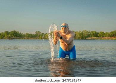 athletic, overweight senior male swimmer splashing himself in a lake in Colorado - Powered by Shutterstock