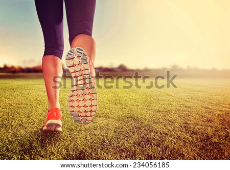  an athletic pair of legs on grass during sunrise or sunset - healthy lifestyle concept 