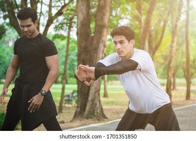 Athletic runner doing stretching exercise, preparing for morning workout in the park